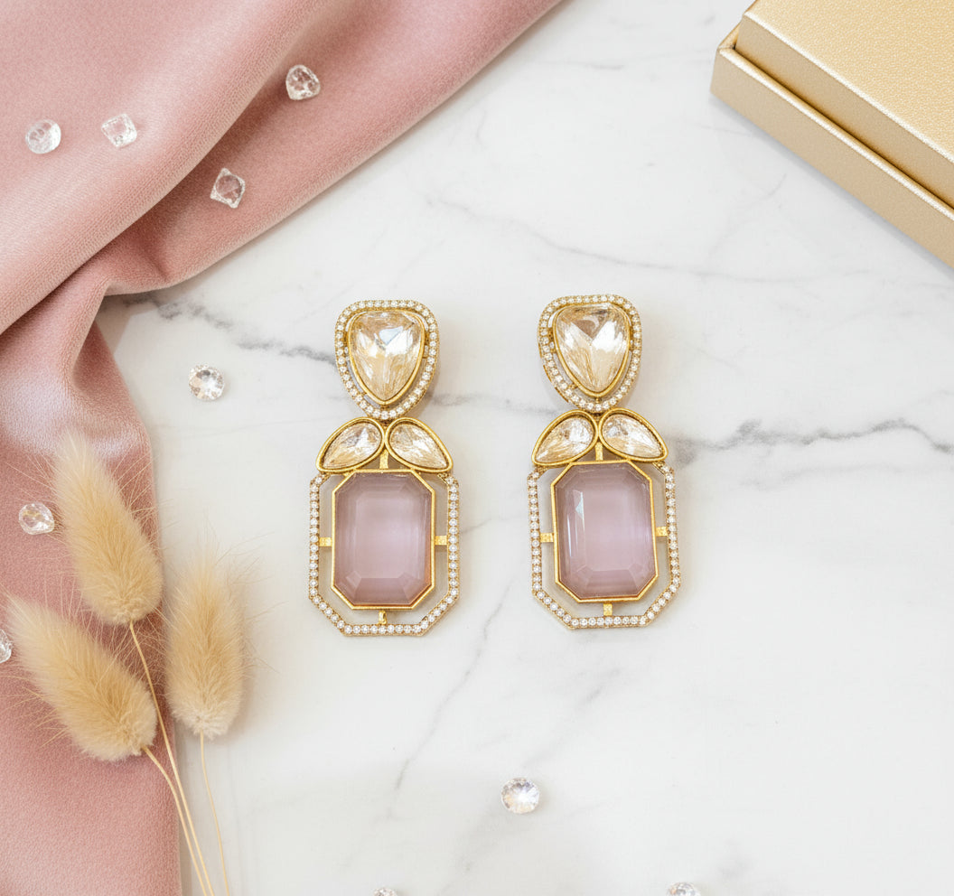 Pair of gold and pink gemstone earrings on a dark background